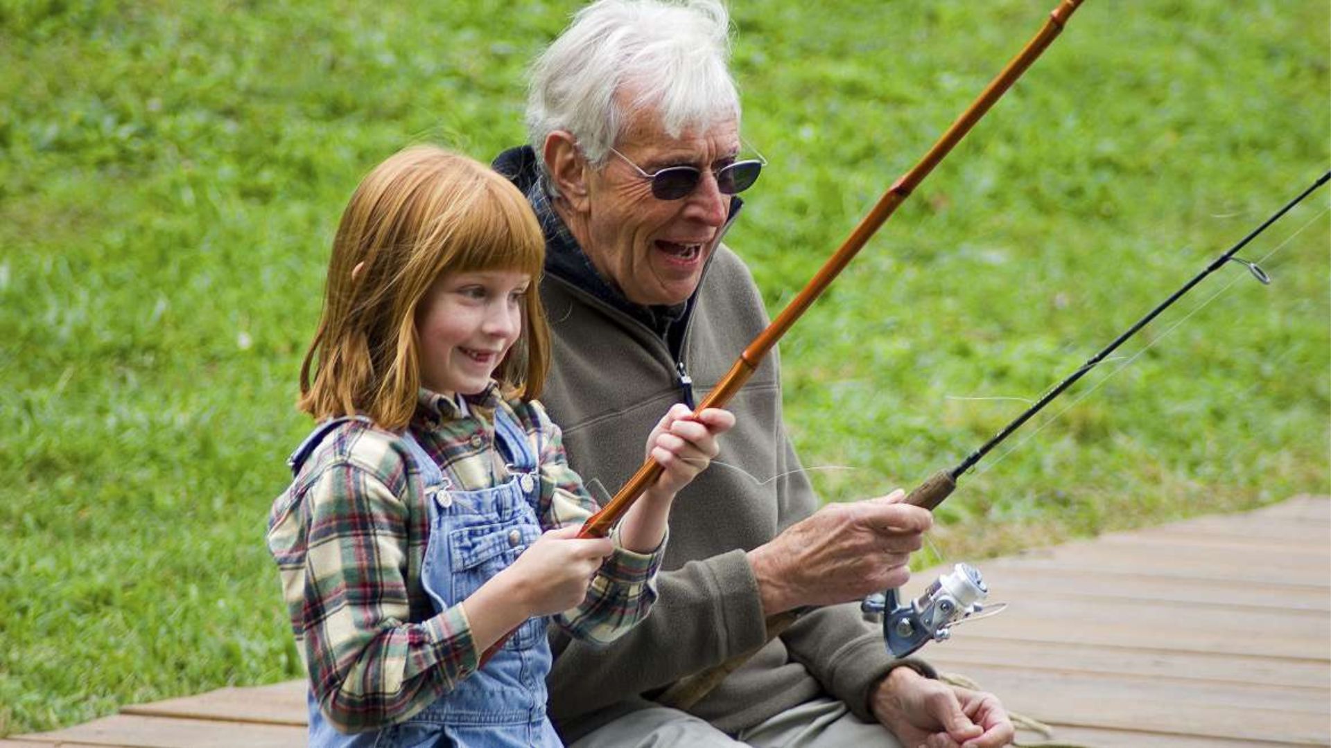 a little girl with her grandfather holding fishing rods